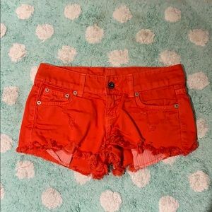 Red Carmar jean shorts with distressing.